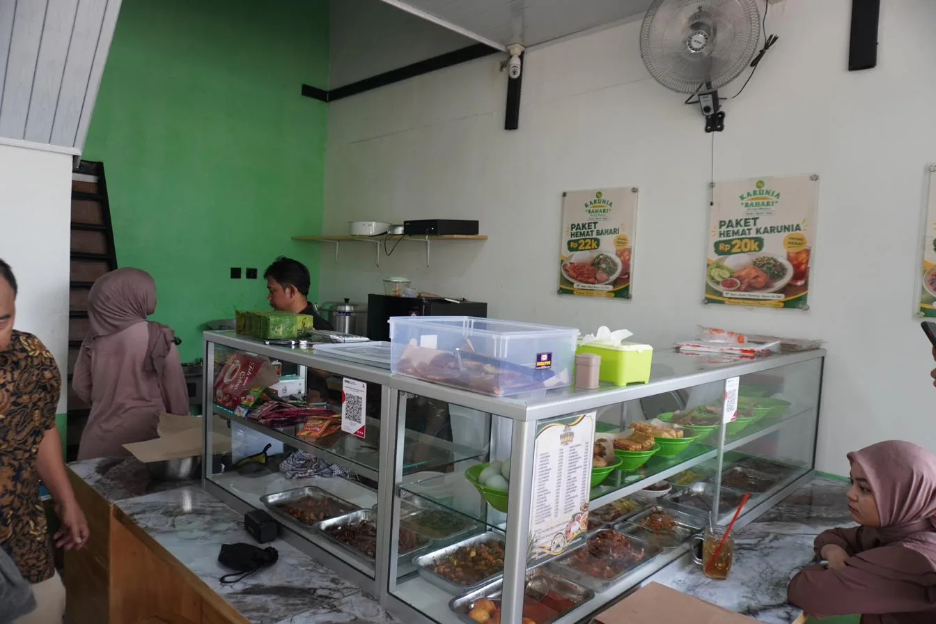 Interior outlet dengan etalase display makanan higienis dan poster paket hemat Warteg Karunia Bahari